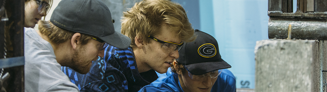 Engineering students in safety glasses examine a structure