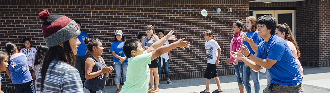 A teacher watches as students play on a playground.