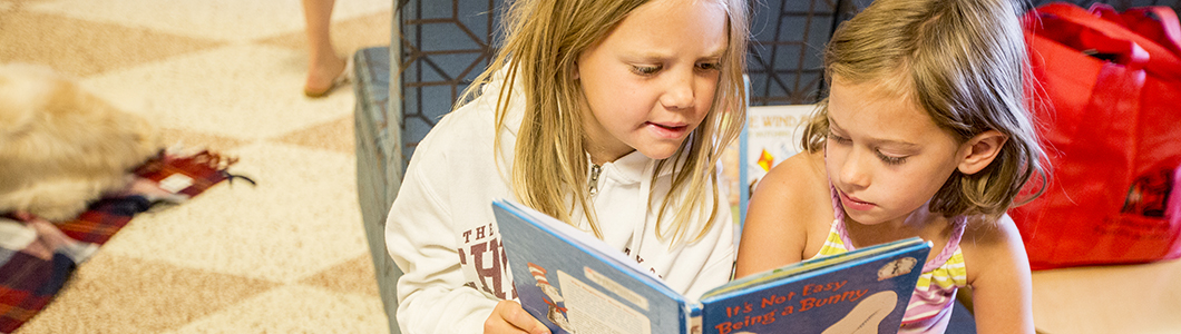 Two kindergarten girls read a book together