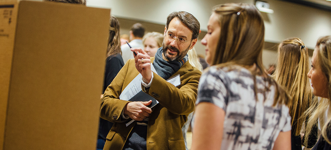 A professor critiques a student's project at the annual design fair.