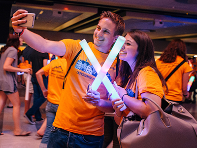 Two students at the MSU block party hold glow sticks and pose for a photo.