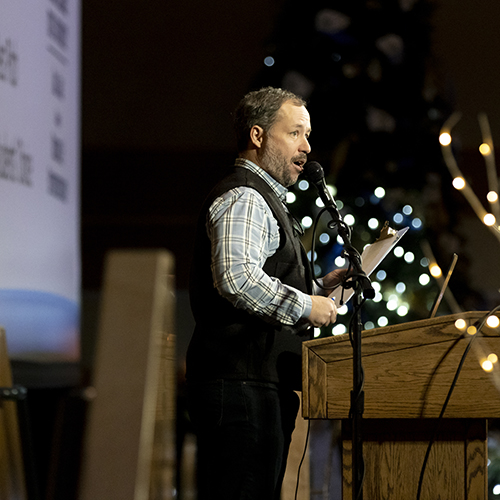 Mark Hom stands at a podium on a stage in the SUB Ballrooms