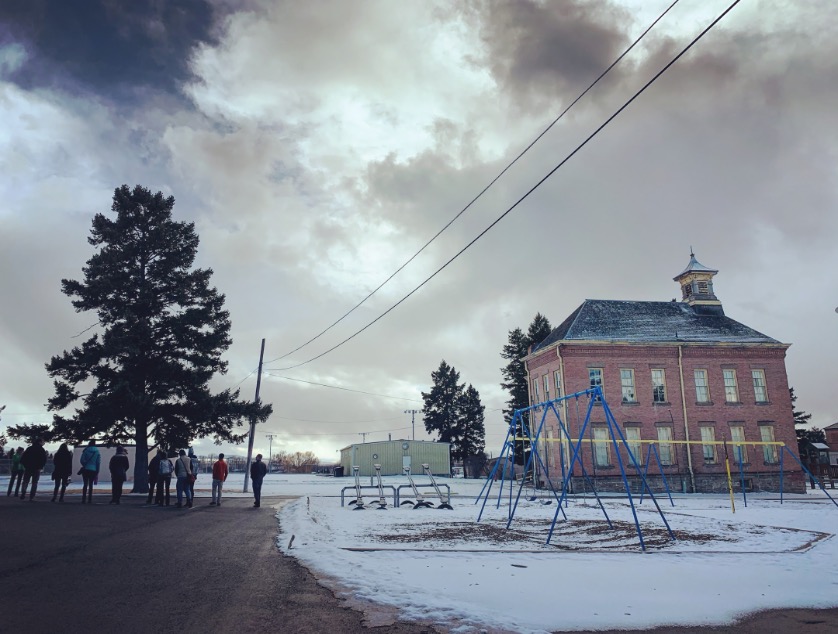 Students and a swingset in front of the Cardwell school building