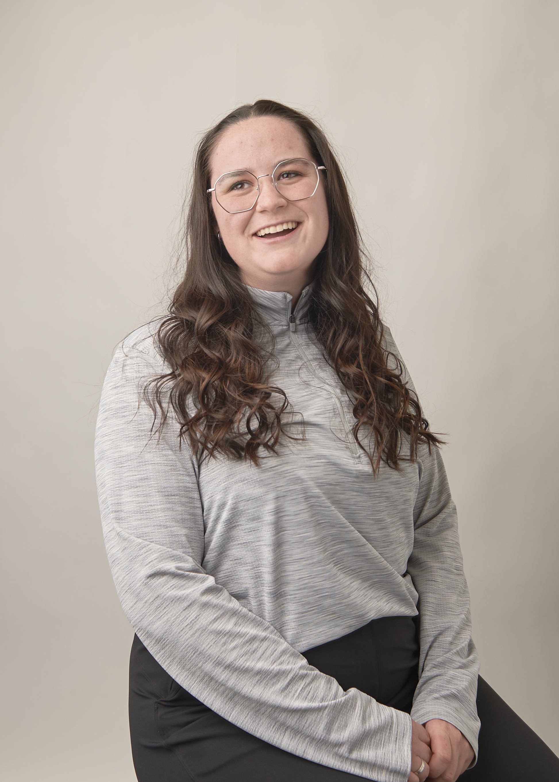 Mackenzie is pictured, sitting on a stool and smiling.