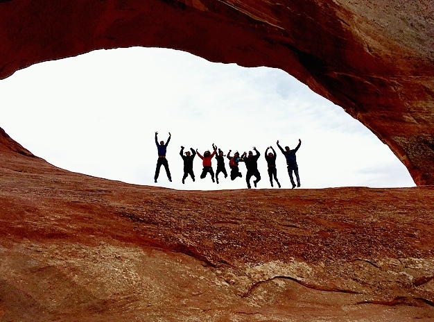 Group Jumping in a backlight natural archway