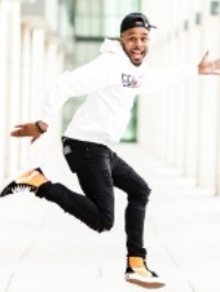 photo of man in his 20's jumping with backwards hat on his head. 