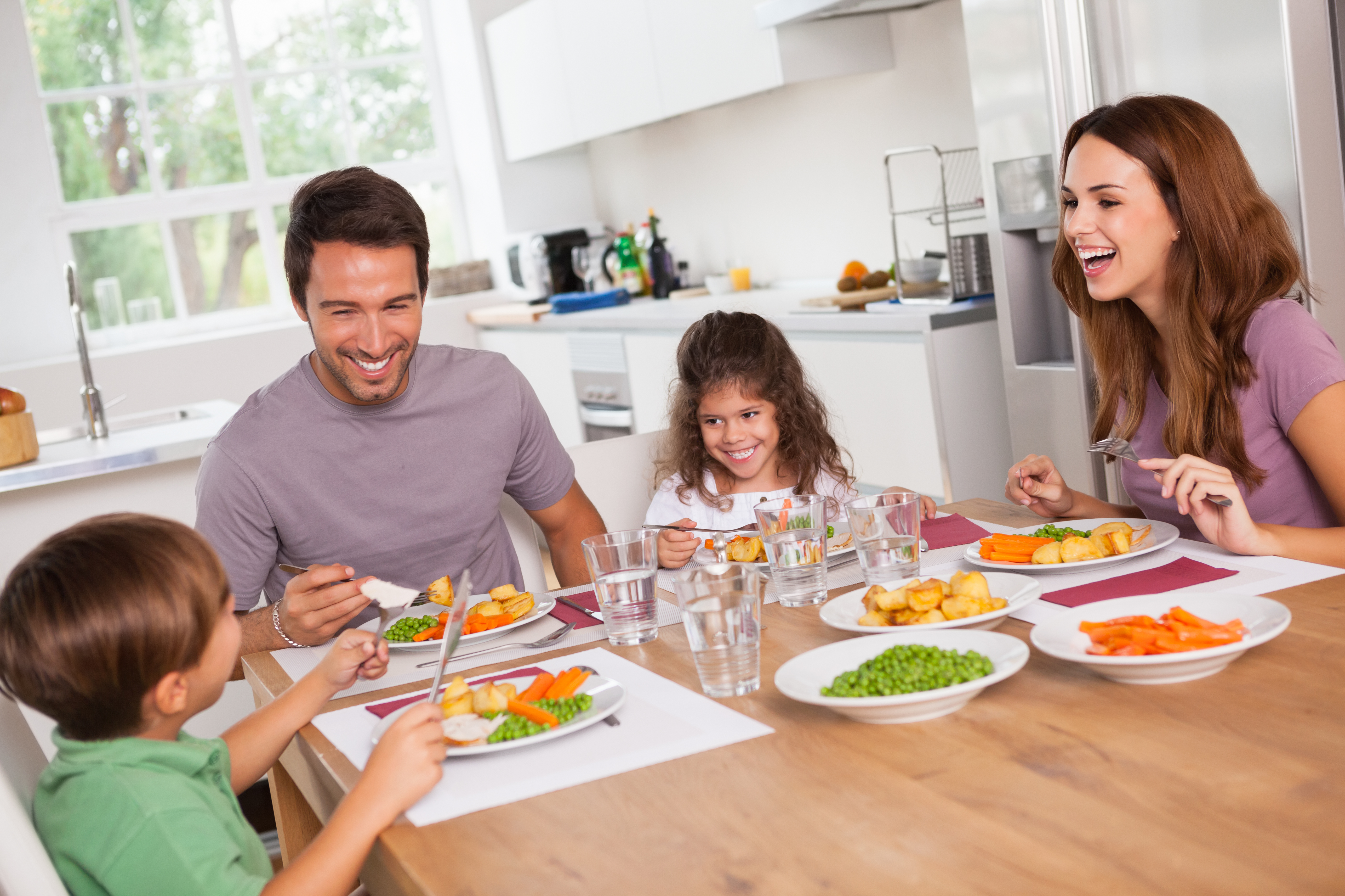 A family of four sitting down at a table for a meal.