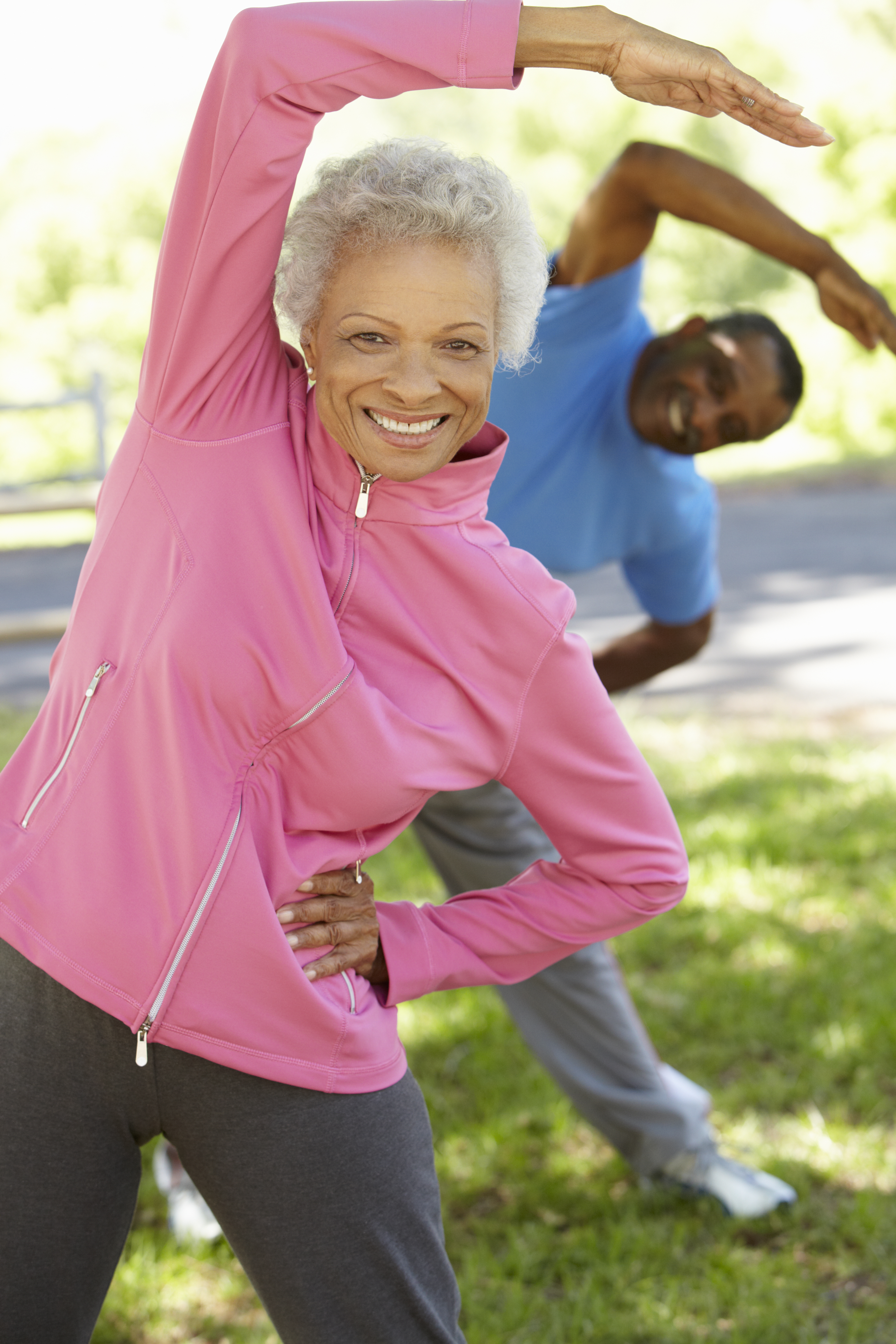 A woman in a pink longsleeve shirt and a man in a blue shirt stretching.