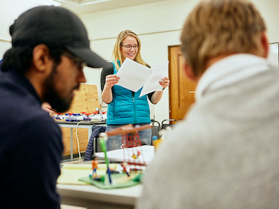 photo of woman looking at pages and smiling as part of project involving two classmates