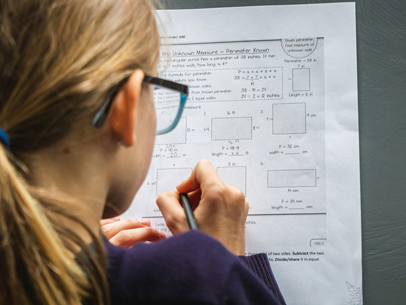 View from behind a girl doing math on a piece of paper