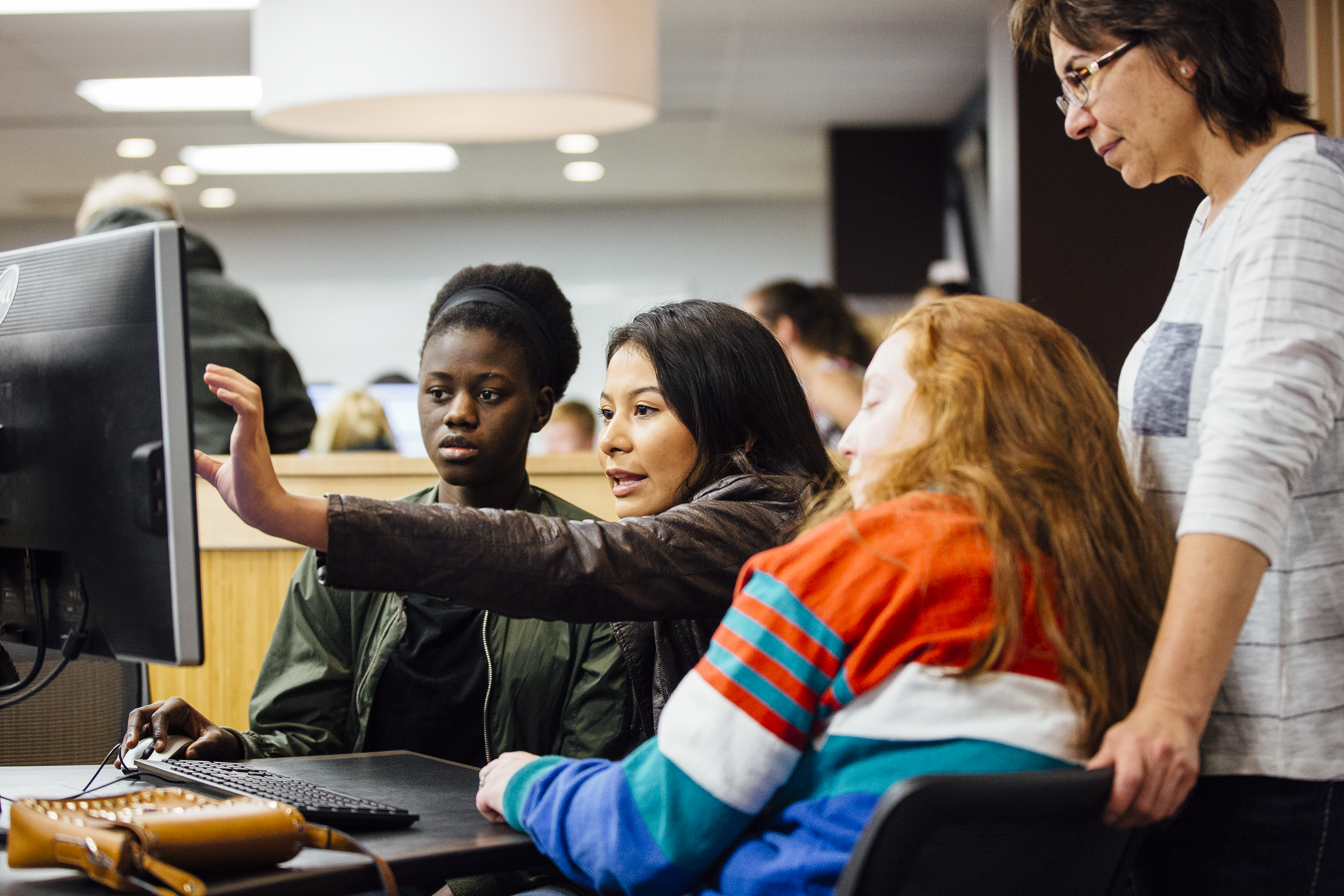 four people looking at computer